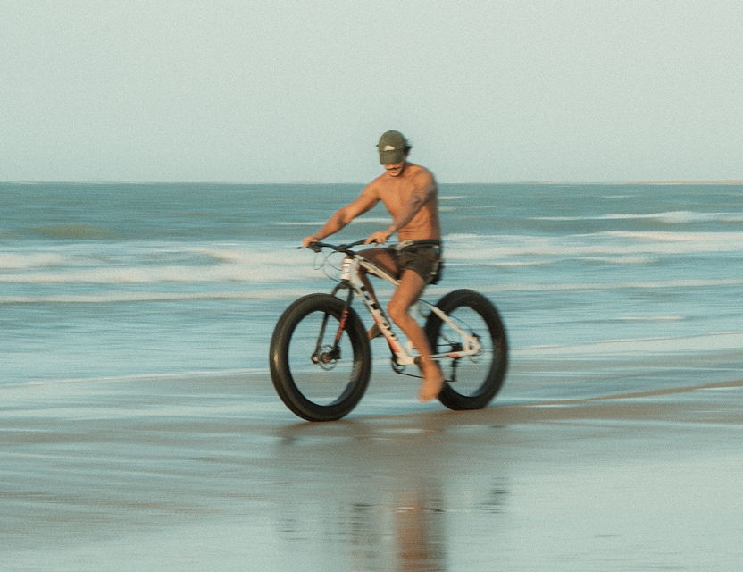 Turista com bicicleta na praia de Icaraizinho, passeio disponível no Aqua de Mar