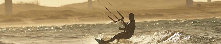 Praticante de kitesurf em manobra sobre uma onda